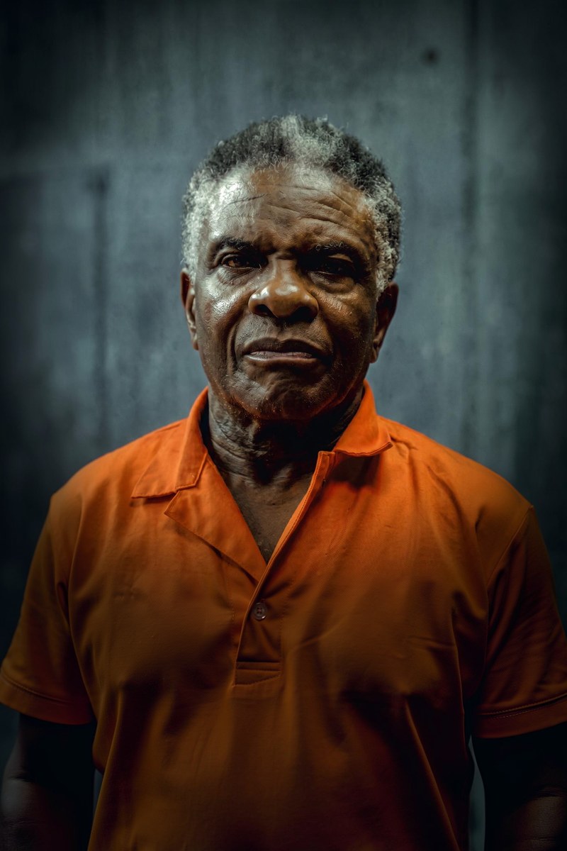 Keith David as Herald, grey-haired and weathered, in an orange prison shirt, looking into the camera