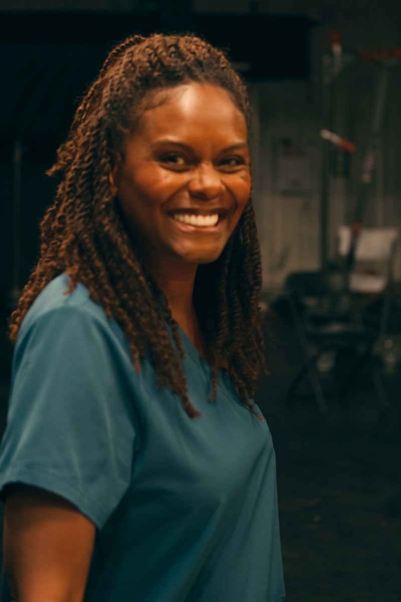 Tabitha Brown as Maria Thompson, smiling, in a blue top