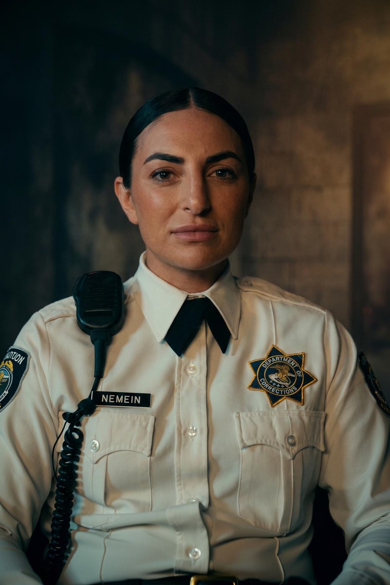 Daria Berenato as Nemein, a corrections officer in her cream uniform shirt